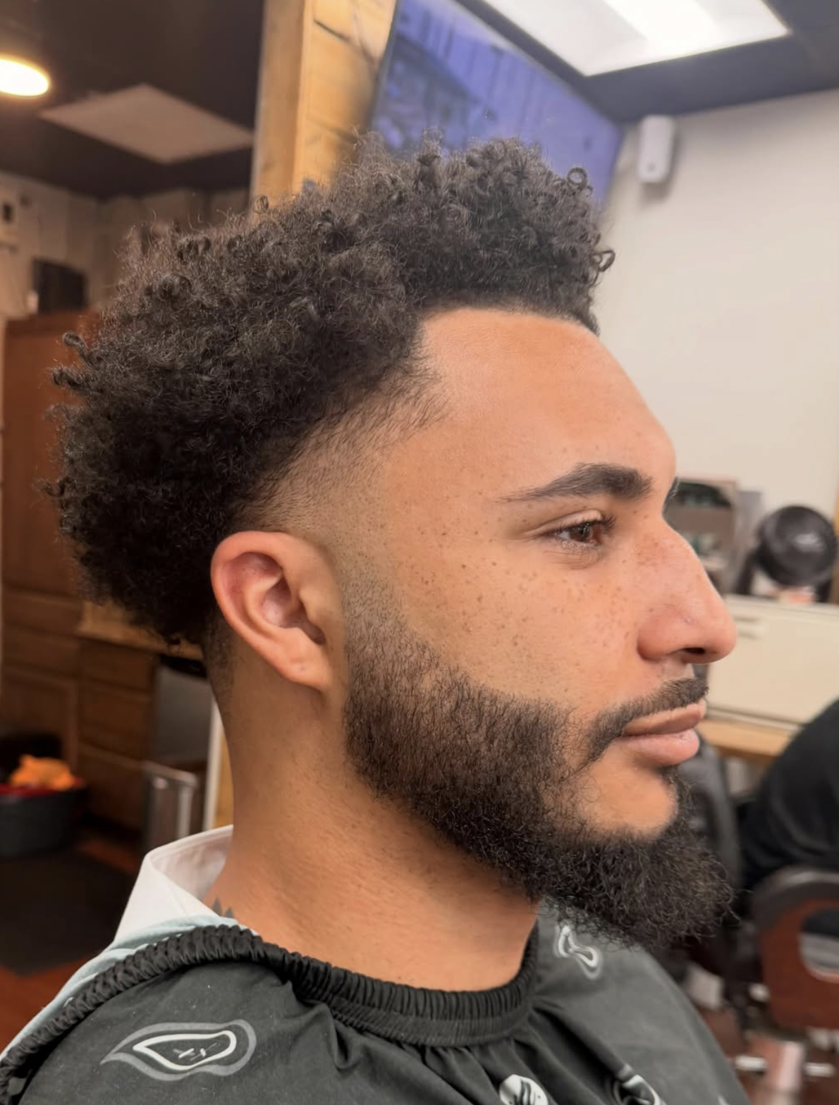Mid fade with a full curly top and crisp edges